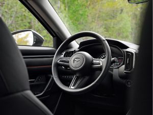 Close up of steering wheel inside unknown Mazda vehicle.