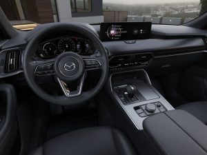 Shot of steering wheel and centre console inside unknown Mazda vehicle.
